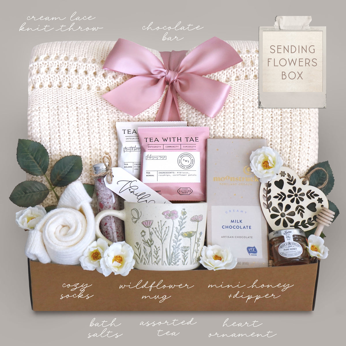 Gift box with tea, flowers, and other items on a gray background
