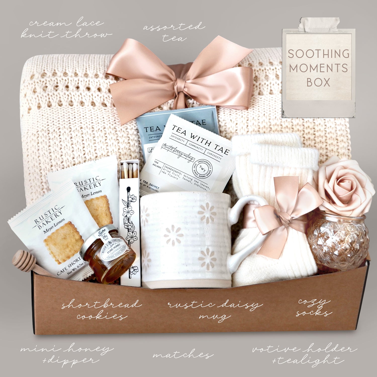 Gift box labeled 'Soothing Moments Box' with tea, cookies, and other items on a neutral background