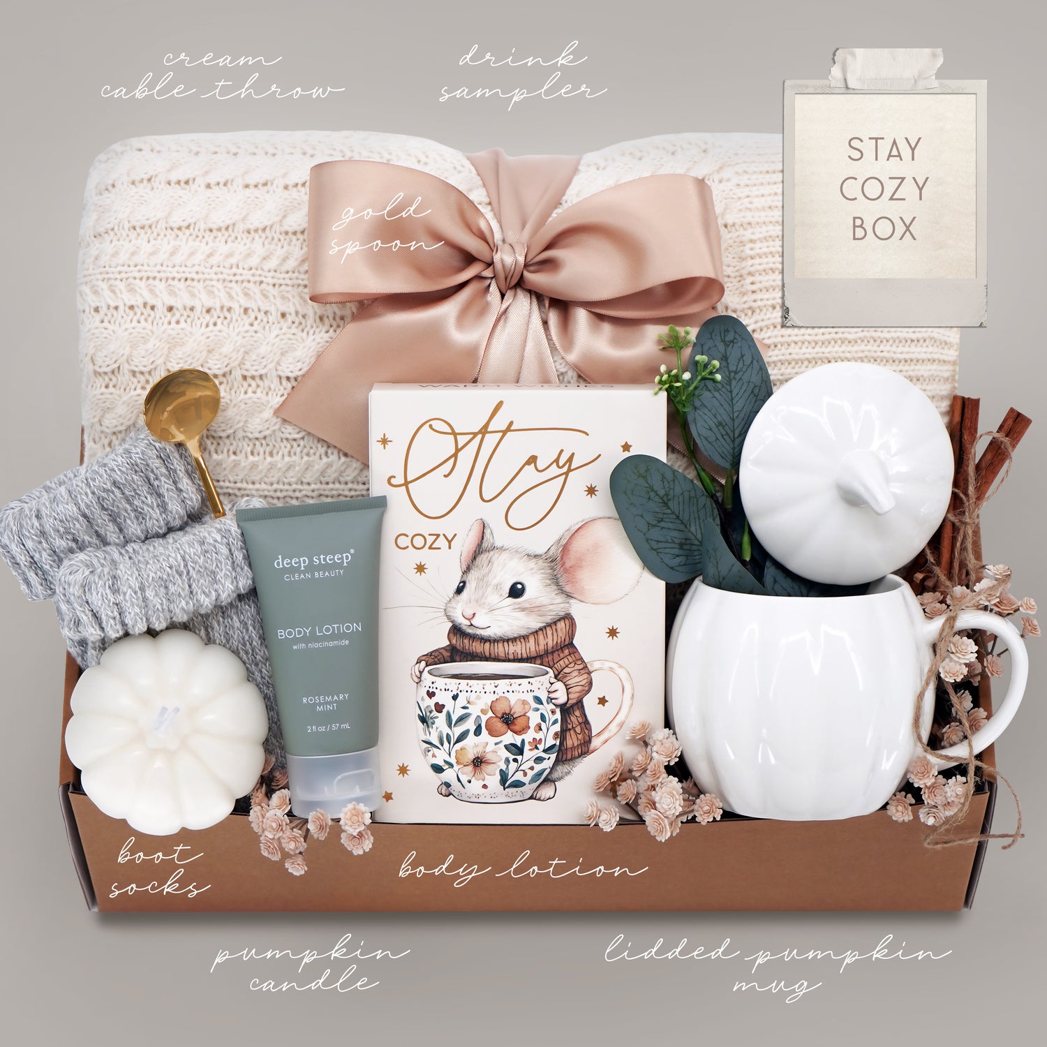 Gift basket with cozy items including a mug, candle, and body lotion on a neutral background