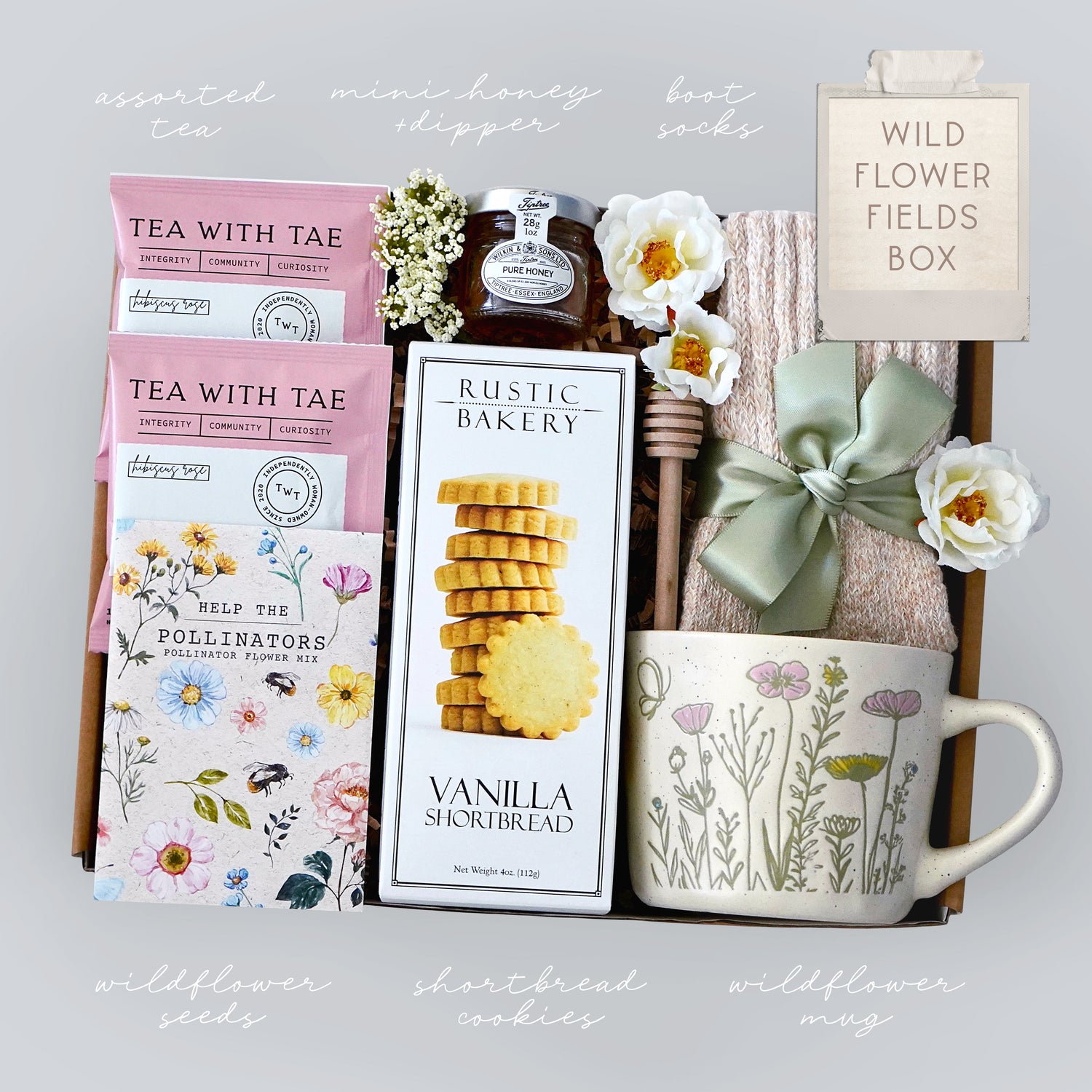 Gift box with tea, cookies, mug, and other items on a light gray background