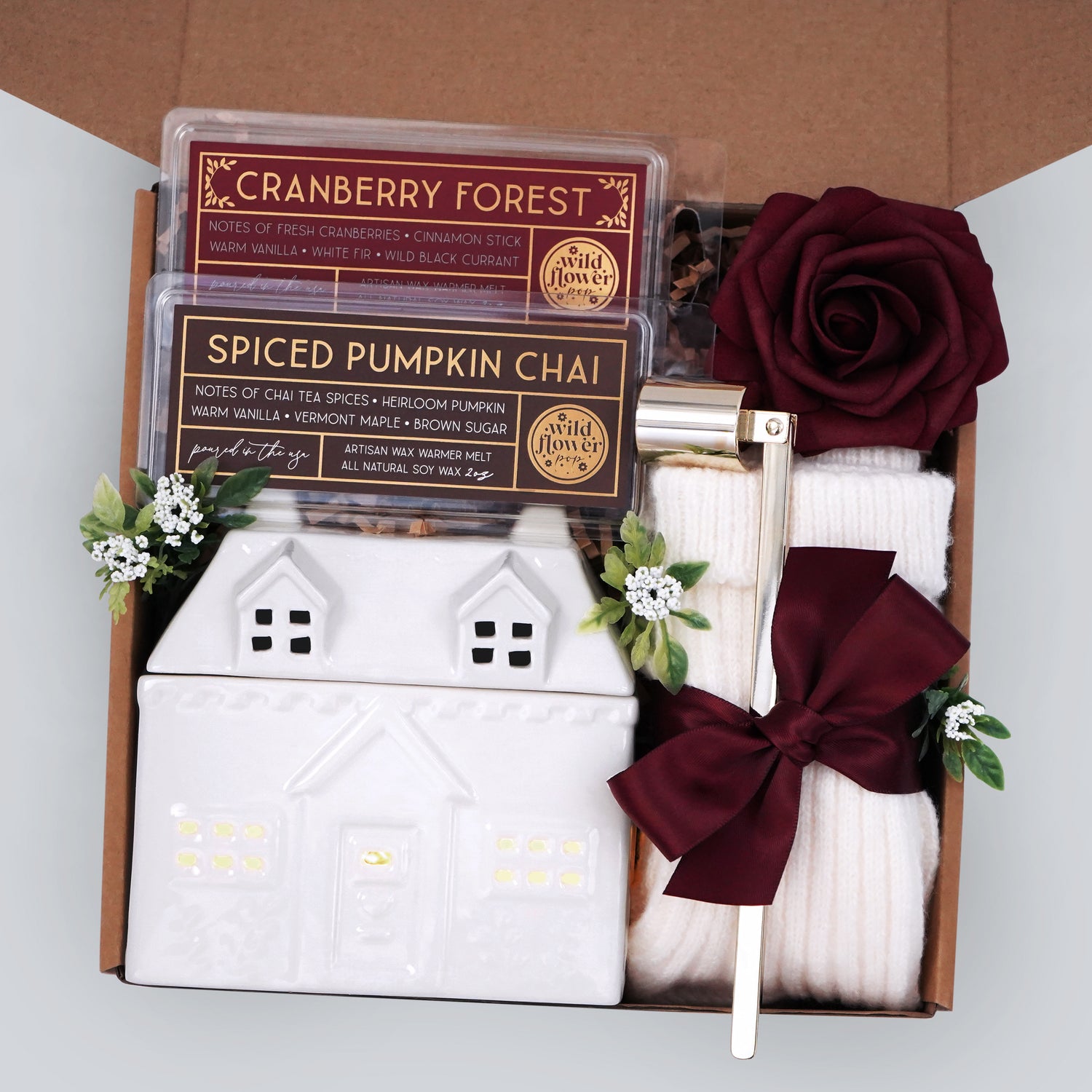 Wildflower Pop exclusive cottage wax warmer, 2 made in the USA 100% soy wax melts, gold candle snuffer, tea light, cream knit socks, with a burgundy faux rose. Packaged and ready to gift.