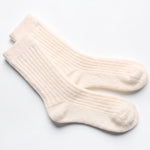 A pair of cream-colored ribbed crew socks laid flat on a clean white background.