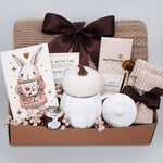 Gift basket with a blanket, drink sampler, and decorative items on a light gray background