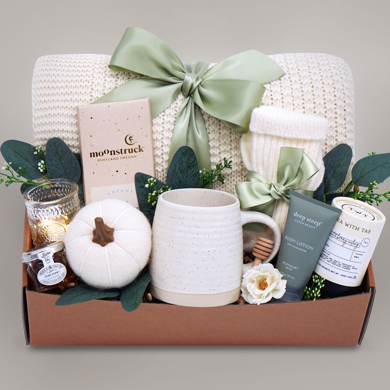 Gift box with a mug, candle, and other items on a gray background