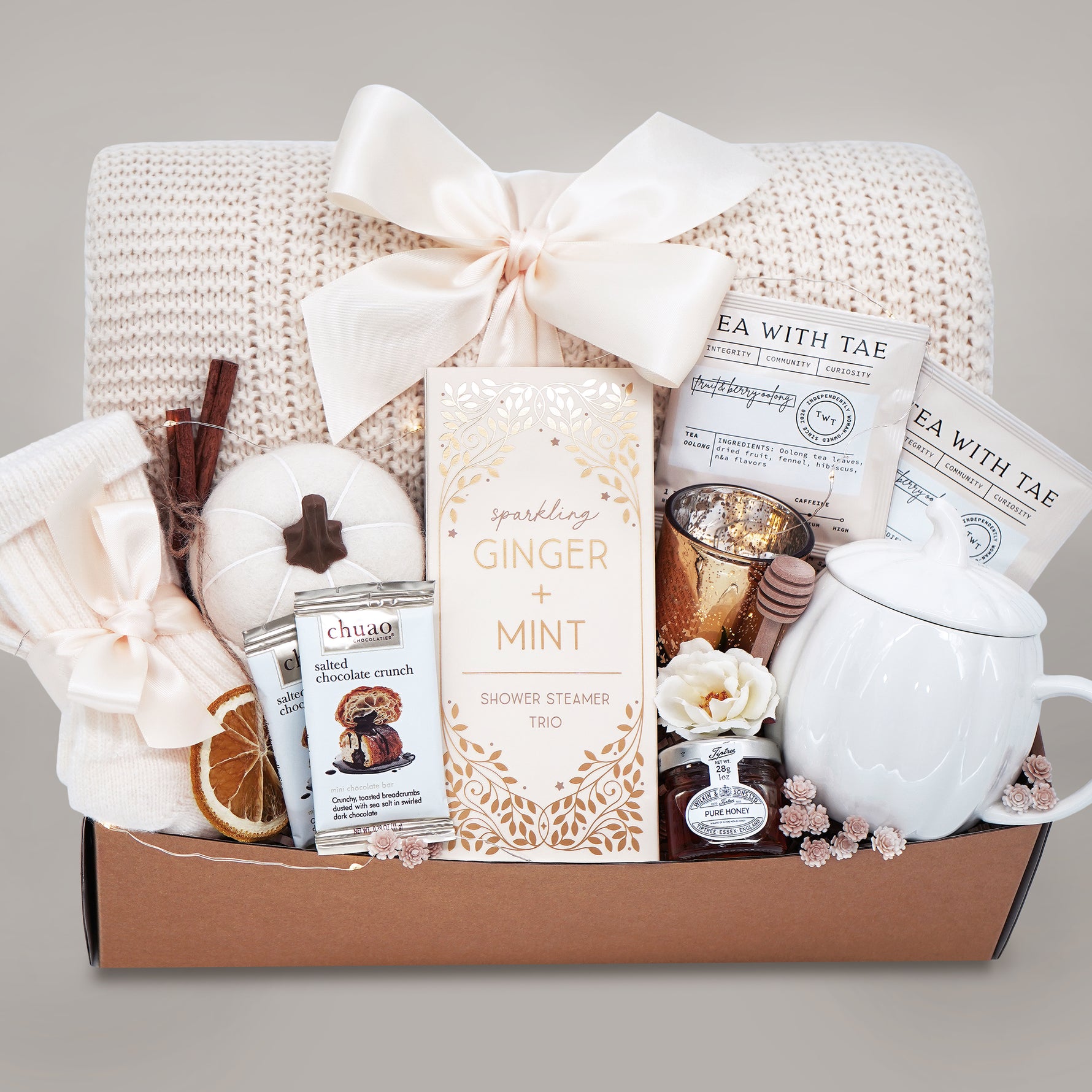 Gift basket with tea, candles, and other items on a gray background