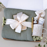 Ivy and Honey Gift Box comes with a sage green lace knit throw tied with cream ribbon, floral notebook, gold ballpoint pen, lavender ceramic mug, mini honey and dipper, tea with tae tea tube, and cream knit socks