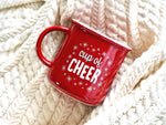 Holiday mug shown is a red ceramic mug with a white rim with the words "cup of cheer" surrounded by snowflakes