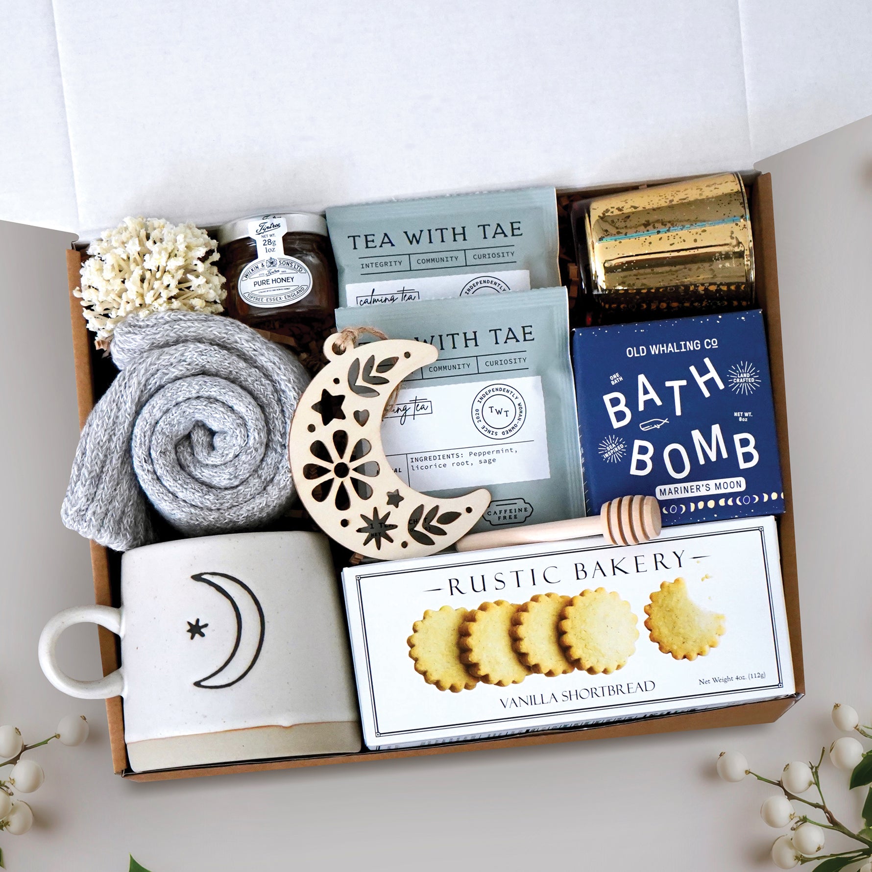 Light of the Moon mug box comes with moon and sun ceramic mug, cozy boot socks, mini honey and dipper, 2 tea bags, moon wood nordic ornament, old whaling co mariners moon bath bomb, votive and tea light