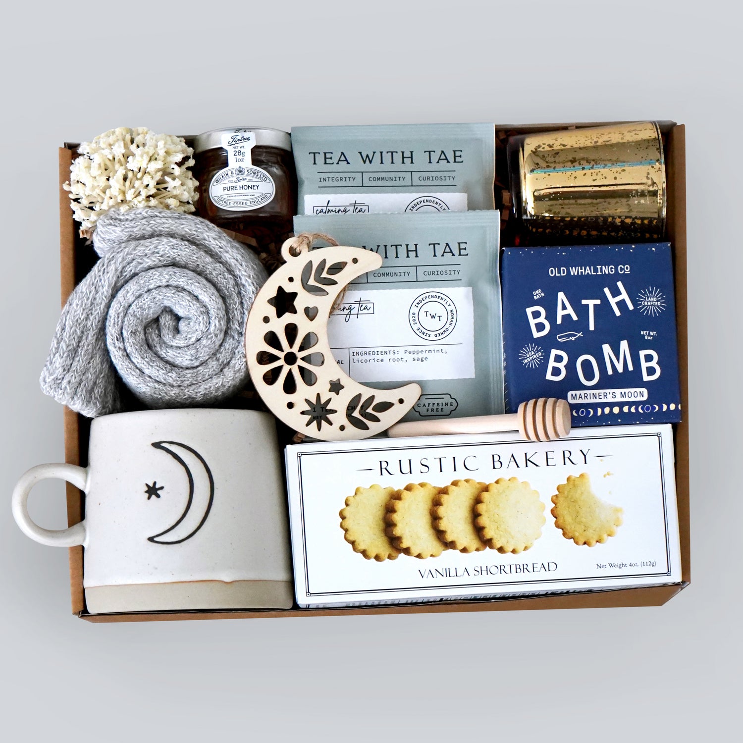 Gift box with tea, cookies, and bath products on a light gray background
