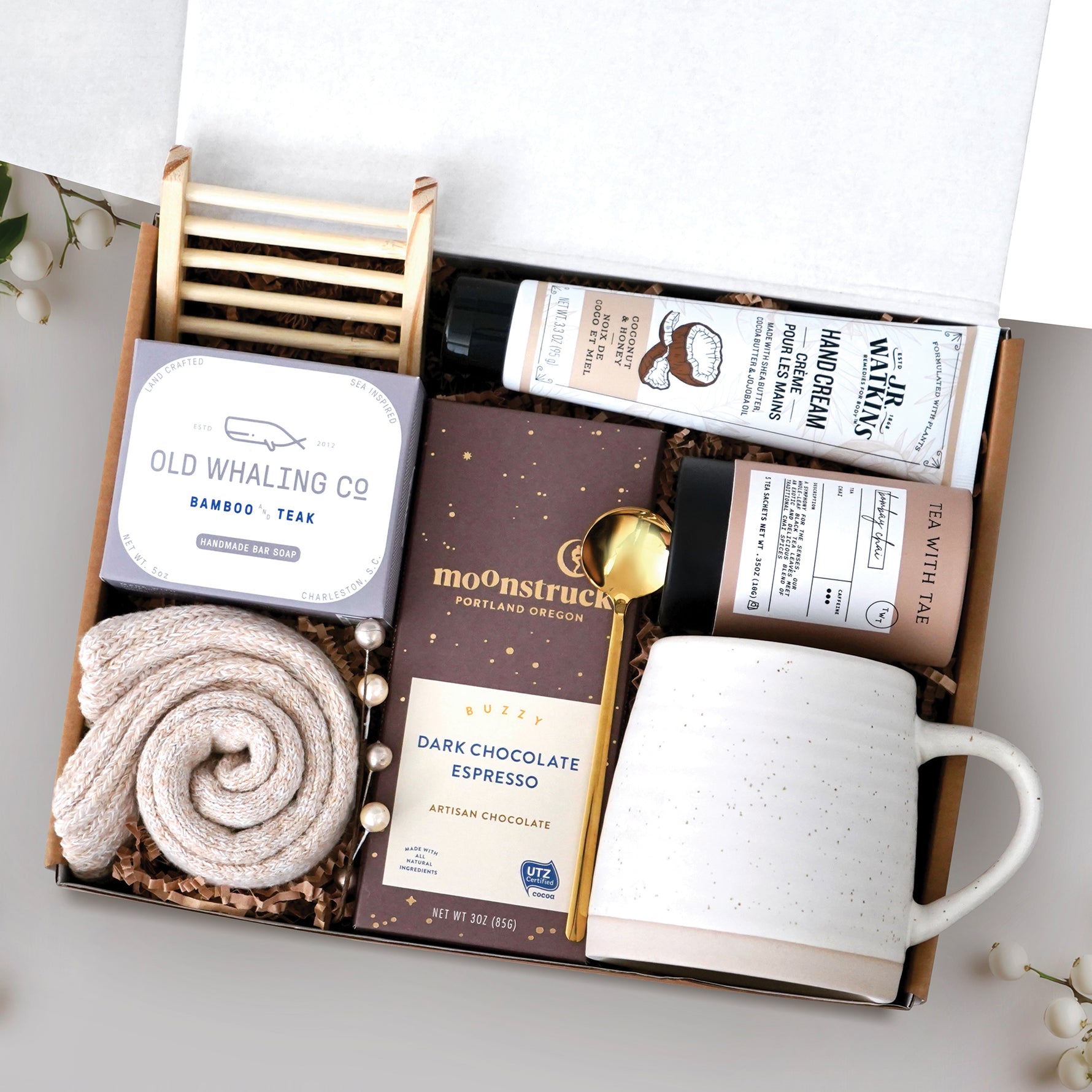 The Nicely Neutral Mug Gift Box comes with a ceramic beehive mug, old whaling co bamboo and teak bar of soap, cozy boot socks, bamboo soap rack, moonstruck espresso dark chocolate bar, gold spoon, tea tube with 5 tea bags, and coconut and honey hand cream 3.3 oz