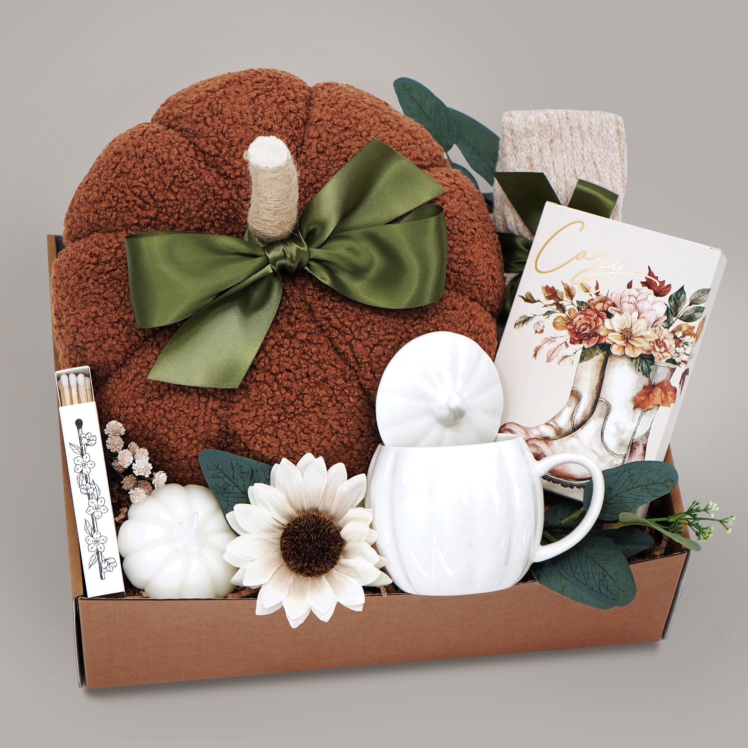 Gift basket with a plush pumpkin, pumpkin mug with lid, and decorative items on a gray background