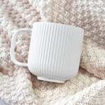 White ribbed mug on a soft beige background