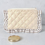 Quilted clutch bag with ruffled edge on a gray background