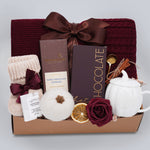 Gift basket with chocolate, tea set, and other items on a light gray background