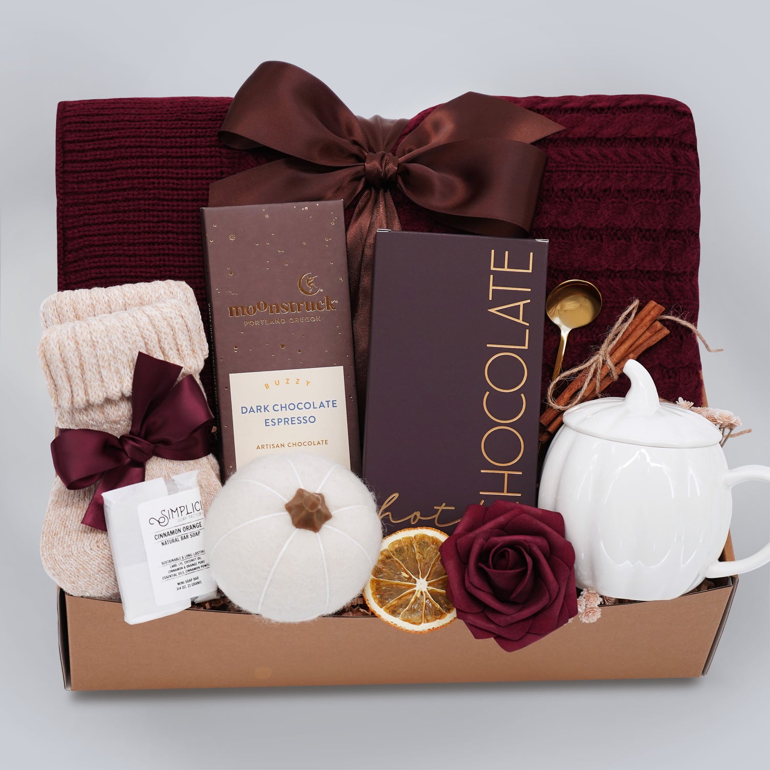 Gift basket with chocolate, tea set, and other items on a light gray background