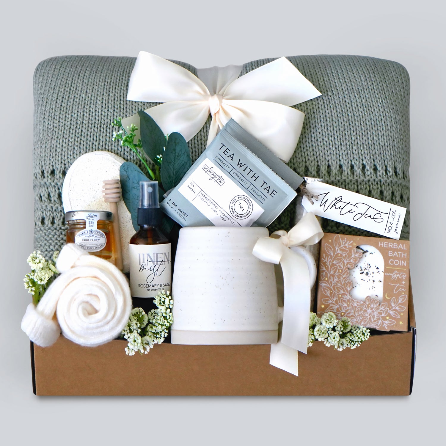 Gift box with tea, soap, and other items on a gray background