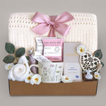 Sending Flowers Gift blanket box with tea, chocolate, and decorative items on a gray background