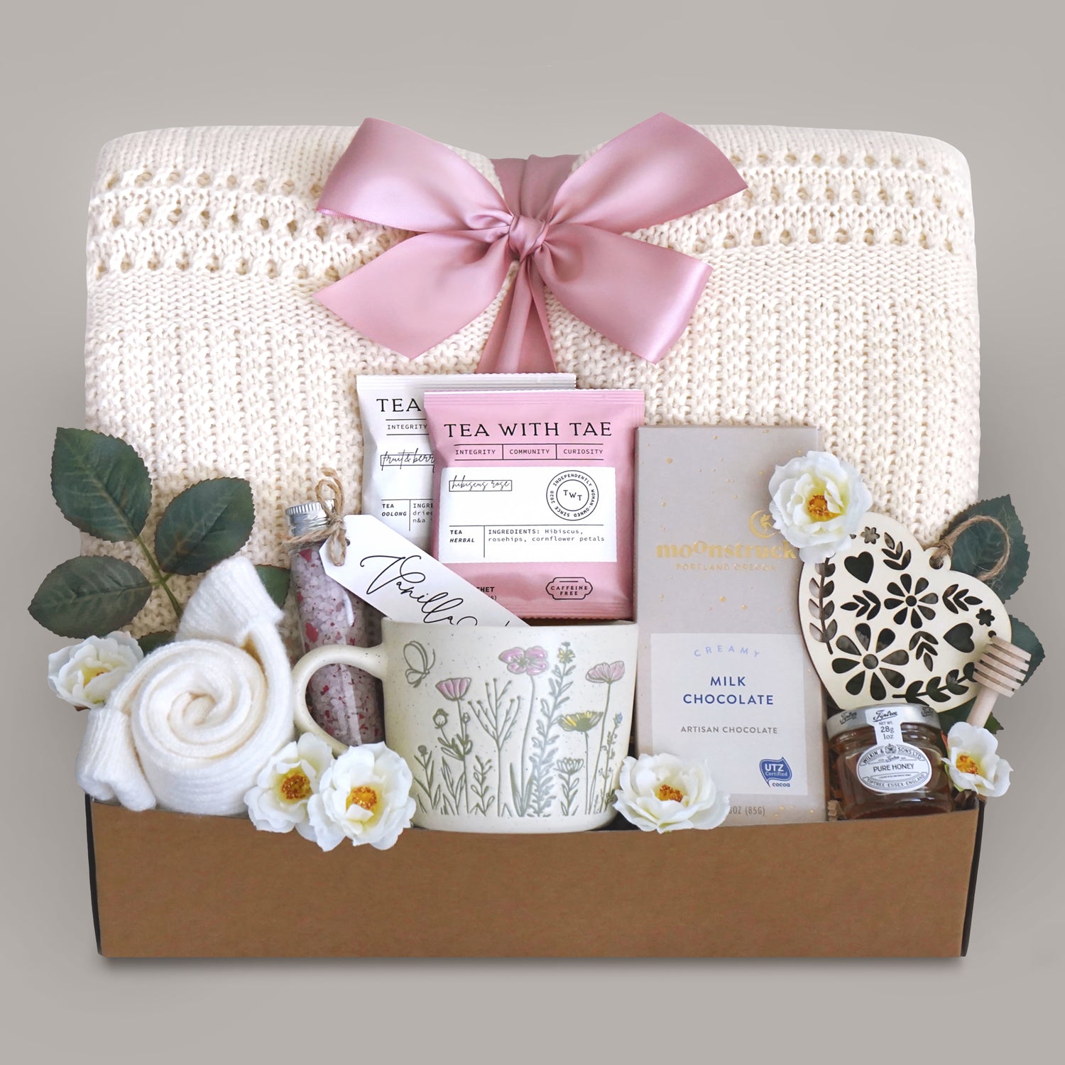 Sending Flowers Gift blanket box with tea, chocolate, and decorative items on a gray background