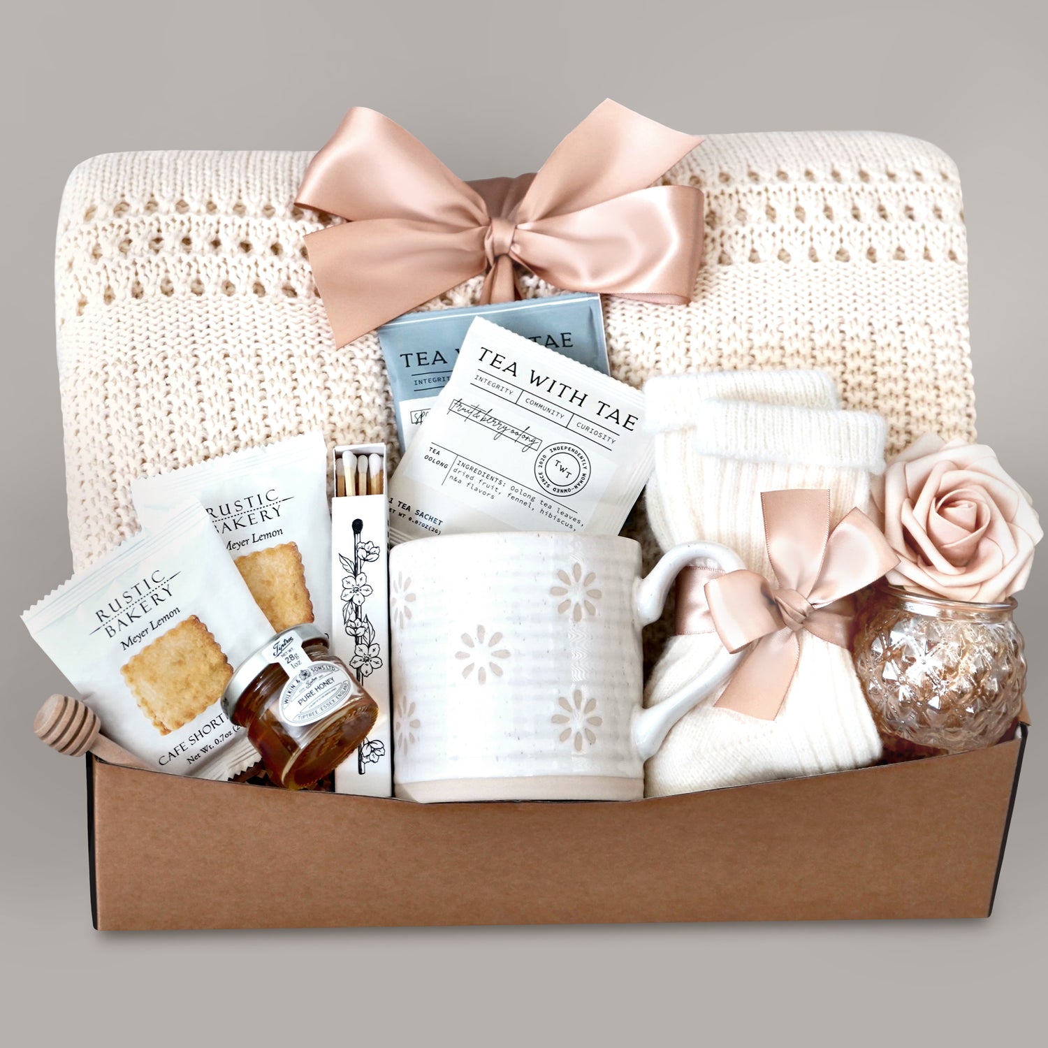 Gift basket with tea, cookies, and decorative items on a gray background
