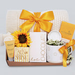 Gift set with sunflower, chocolate bar, and other items on a light gray background