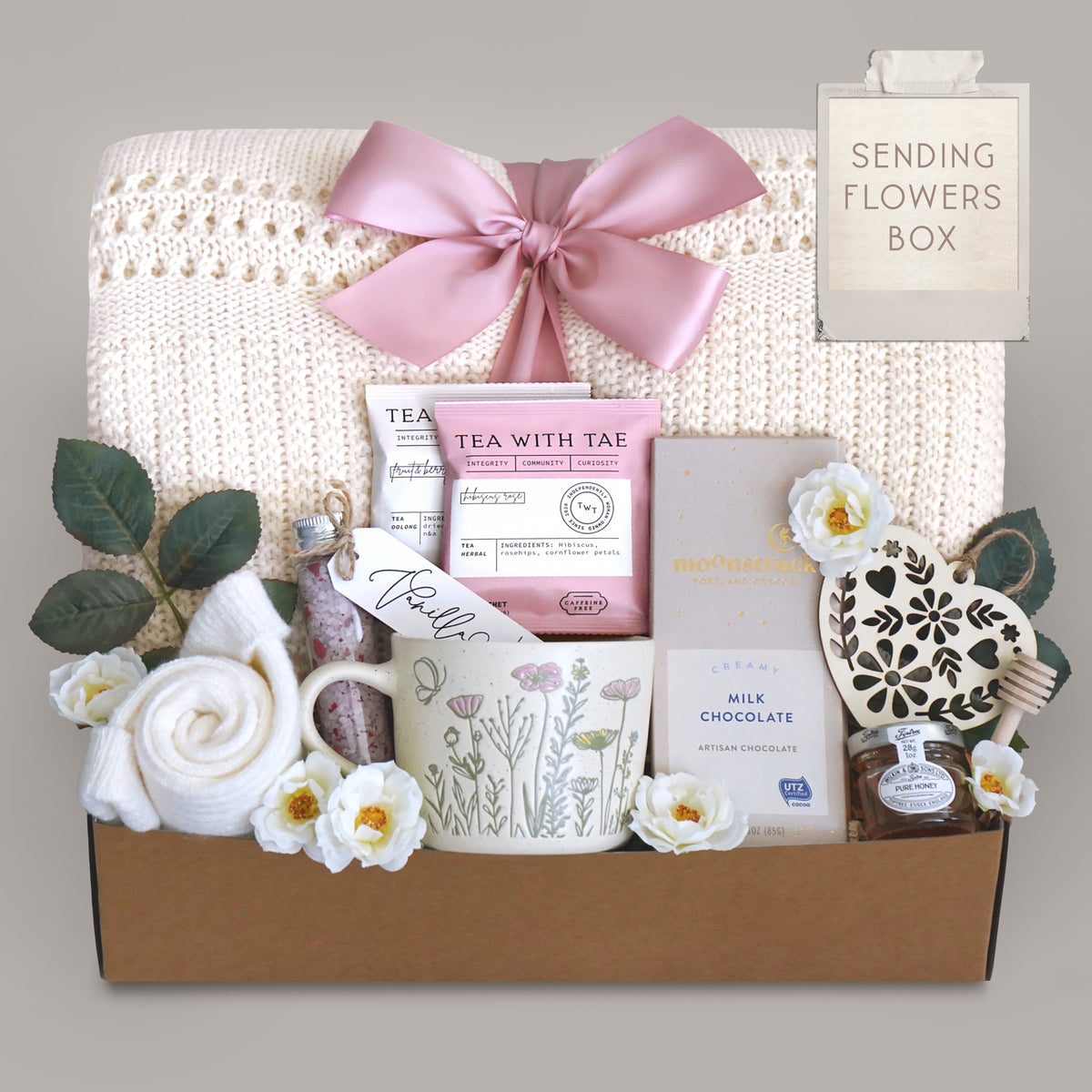 Gift box with tea set, flowers, and a mug on a gray background