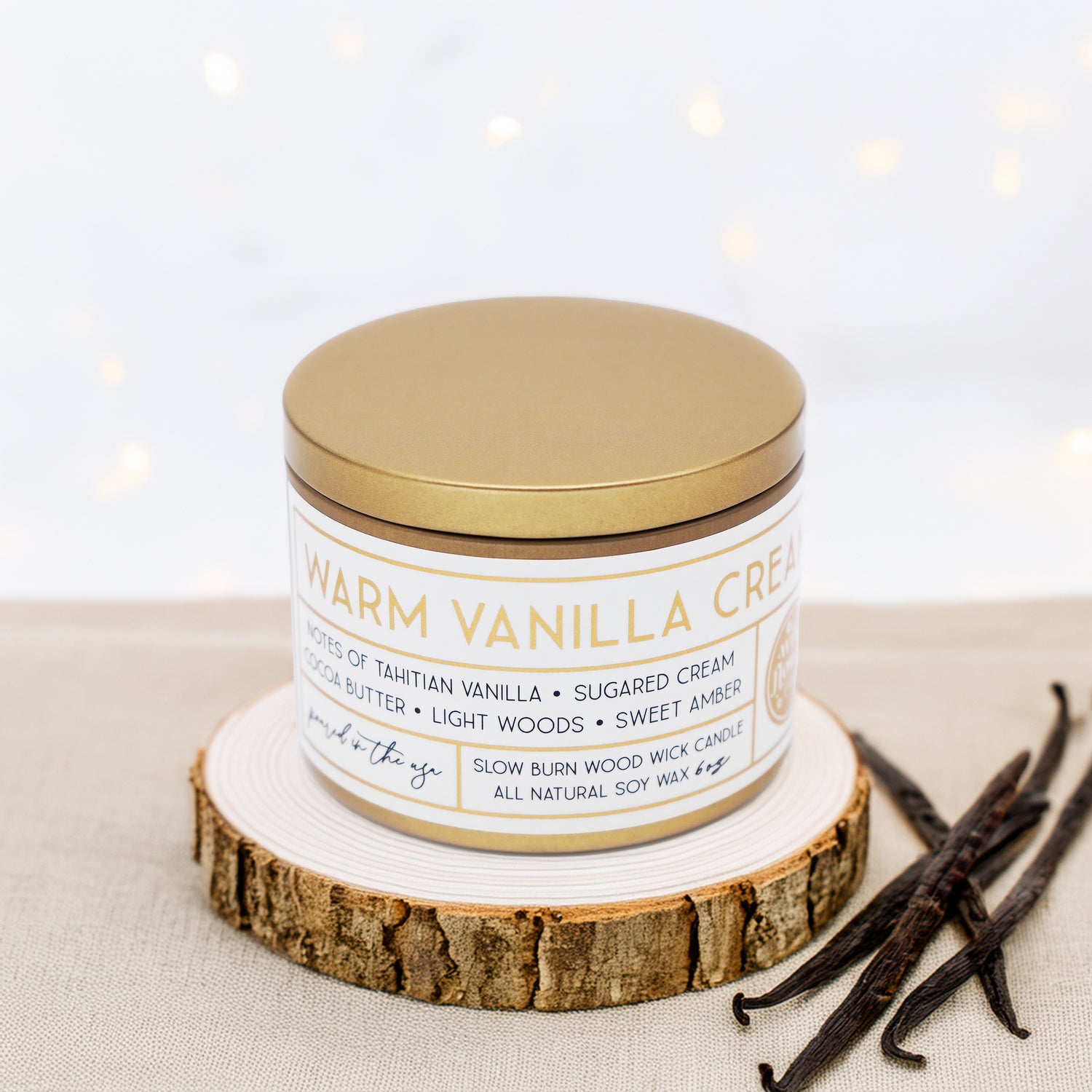 Wildflower Pop Candle labeled 'Warm Vanilla Cream' on a wooden coaster with vanilla beans beside it.