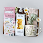 Gift set with tea, cookies, mug, and honey with dipper on a gray background