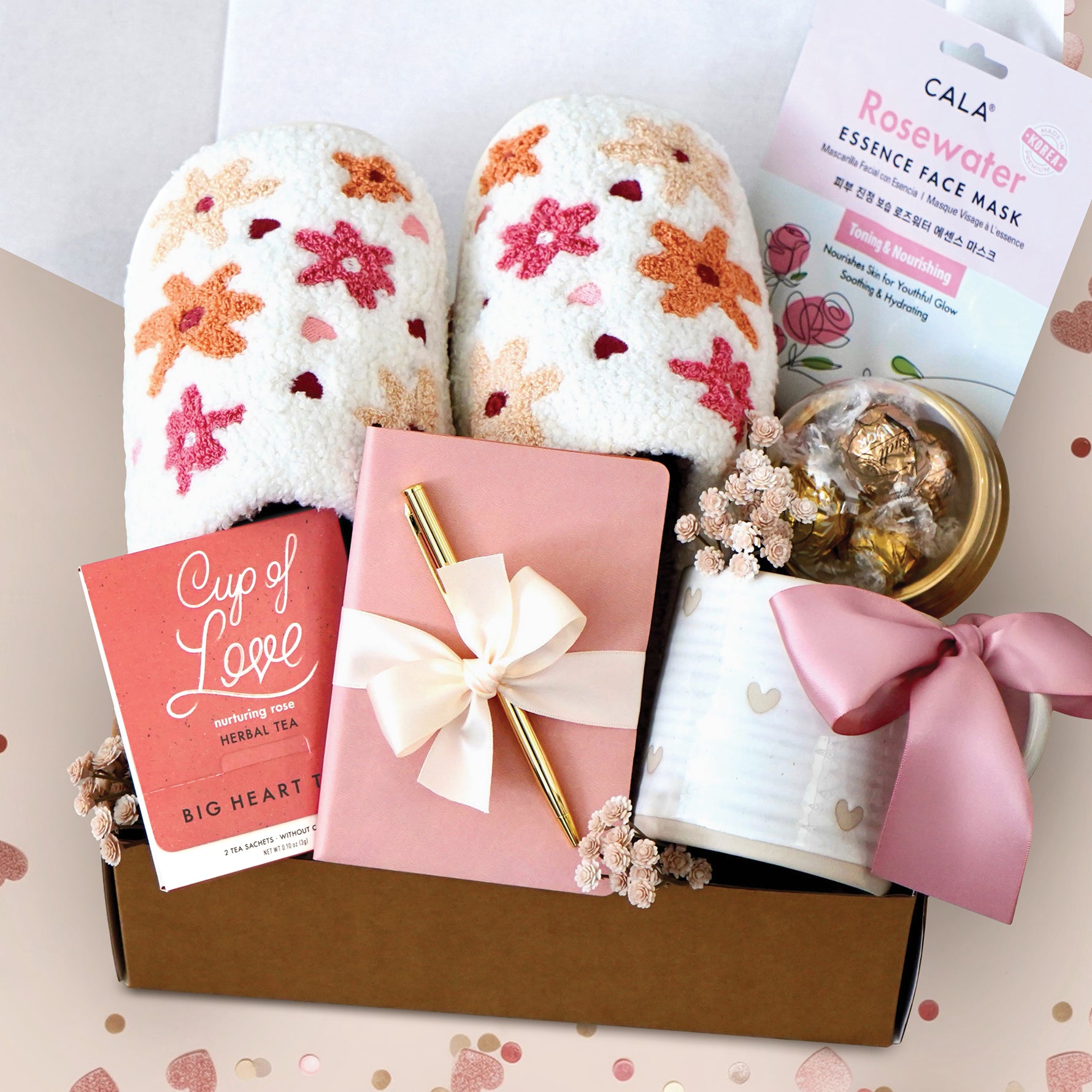 XO Toes Gift Box comes with slippers with flowers and darts in your choice of size, leatherette notebook in either blush, rose, or nude, gold pen, cup of love herbal tea, chocolate truffles, rose water face mask, and rustic heart mug