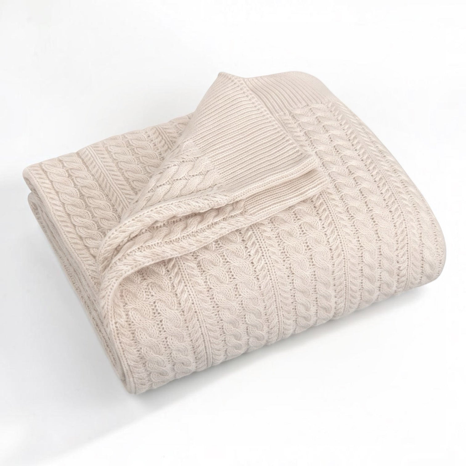 A folded cream-colored cable-knit blanket with a ribbed border, displayed on a clean white background.