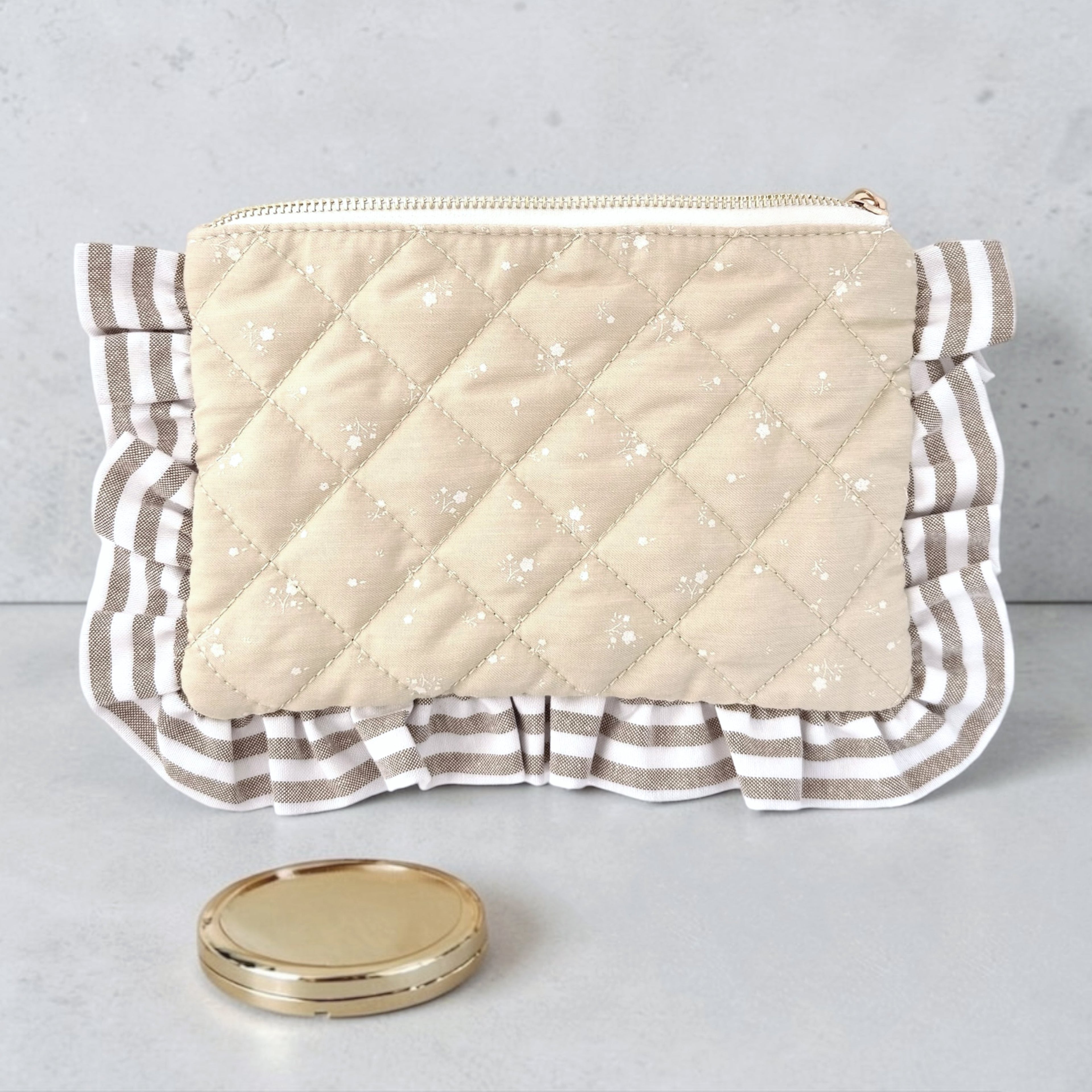 Quilted clutch bag with ruffled edge on a gray background