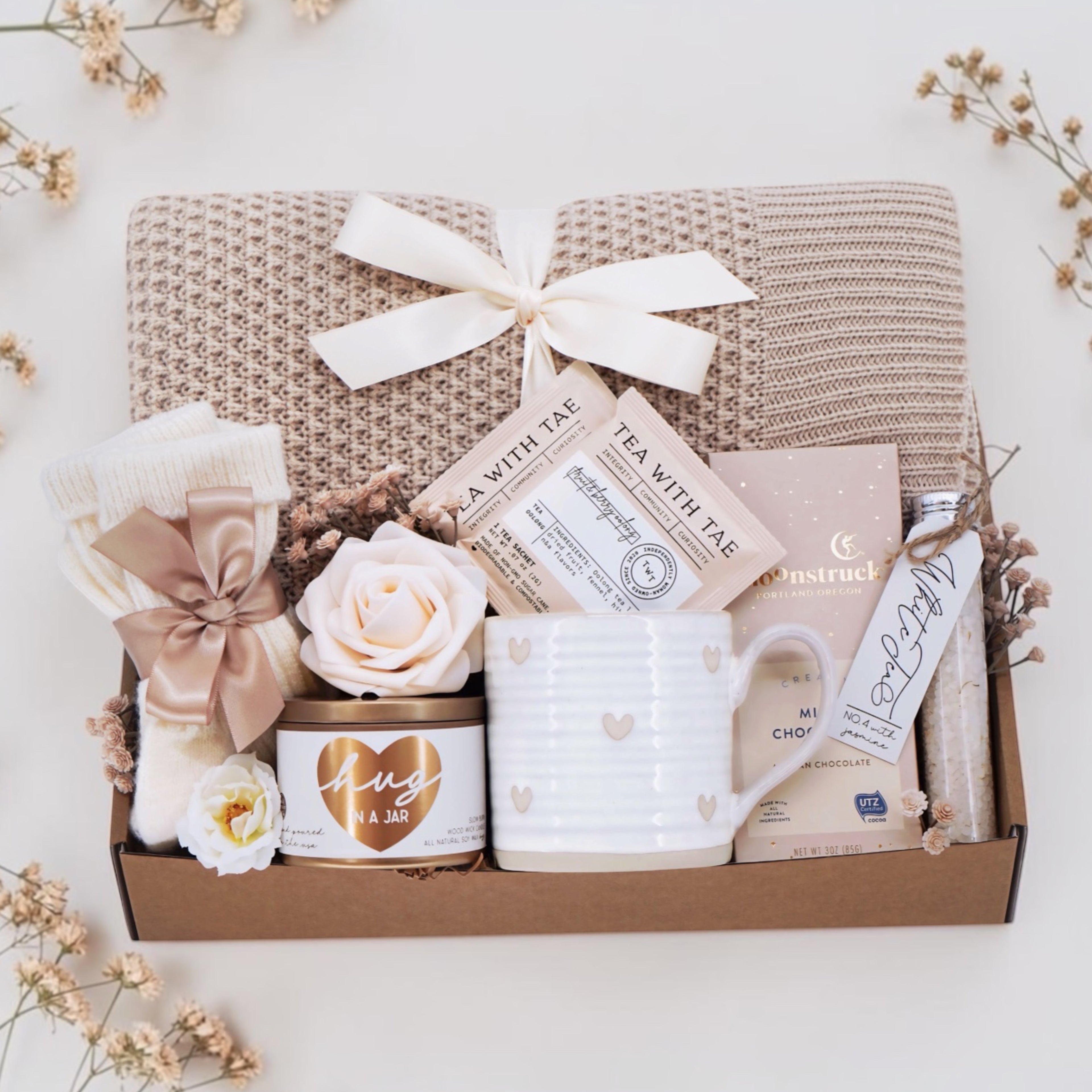 Wildflower Pop Solace and Light blanket gift box comes with honeycomb blanket, cream knit socks, hug in a jar soy wax candle, Wildflower Pop Hearts ceramic mug, 2 tea bags, Moonstruck milk chocolate bar, and floral bath salts