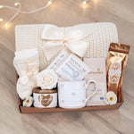 Wildflower Pop Sending a Hug Blanket gift box, with cream lace knit blanket, tea sampler, cream knit socks, hug in a jar soy wax candle, Wildflower Pop Heart ceramic mug, Moonstruck Milk Chocolate bar, and muscle soak