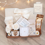 Wildflower Pop Sending a Hug Blanket gift box, with cream lace knit blanket, tea sampler, cream knit socks, hug in a jar soy wax candle, Wildflower Pop Heart ceramic mug, Moonstruck Milk Chocolate bar, and muscle soak