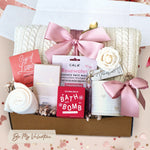 Be My Valentine gift box comes with cream cable knit blanket tied with a blush ribbon, rose face mask, Seaberry and Rose Bath Bomb, milk chocolate moonstruck bar, cream knit socks, cup of love herbal tea, vanilla rose bath salt tube, ceramic hearts mug, gold demitasse spoon, and faux cream rose head