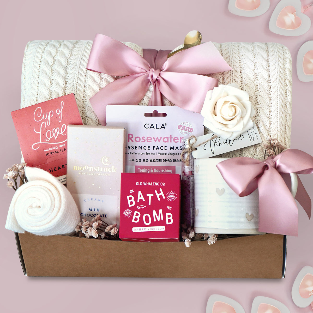 Wildflower Pop Gift box with cable knit blanket,  bath products including a bath bomb, face mask, and tea on a pink background.