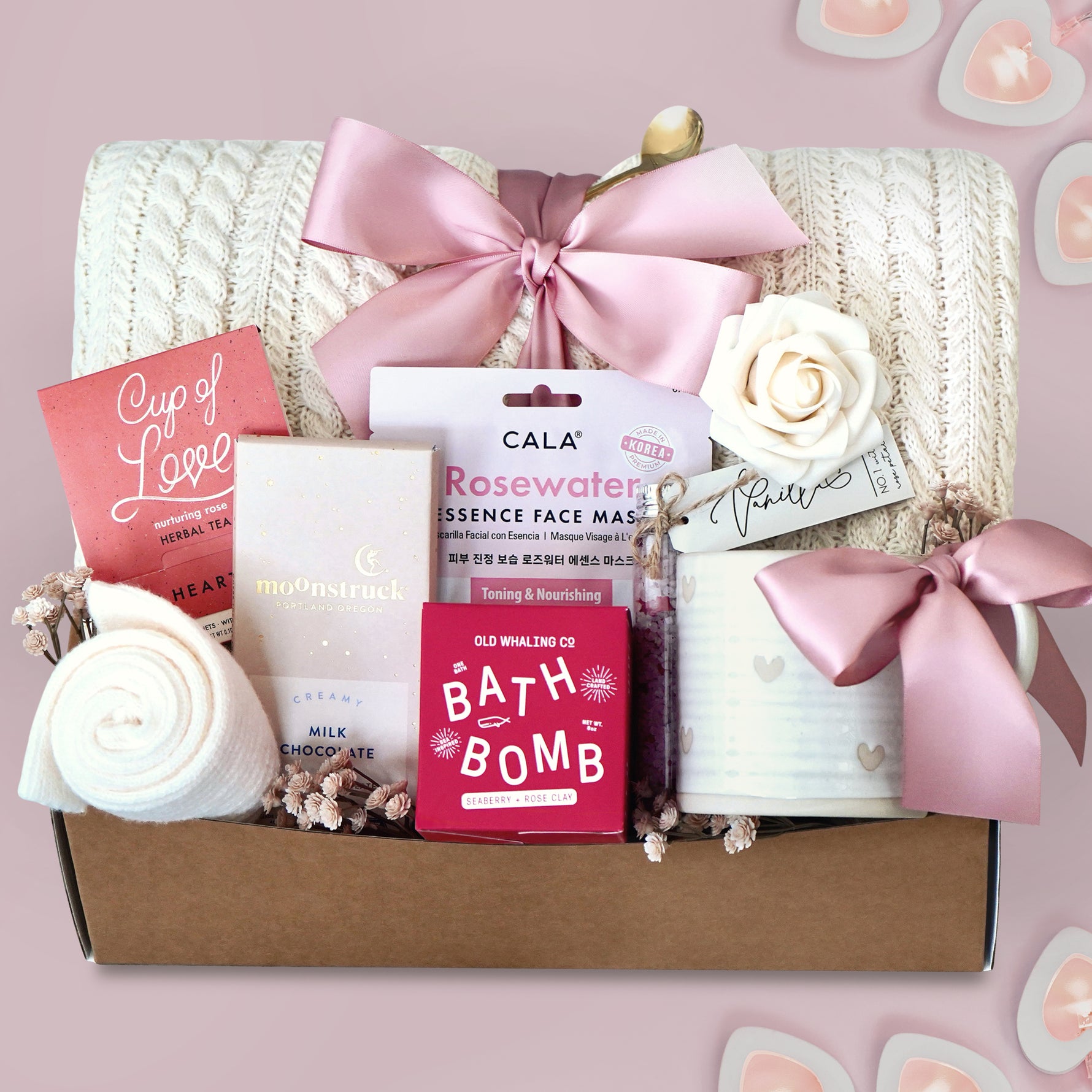 Wildflower Pop Gift box with cable knit blanket,  bath products including a bath bomb, face mask, and tea on a pink background.
