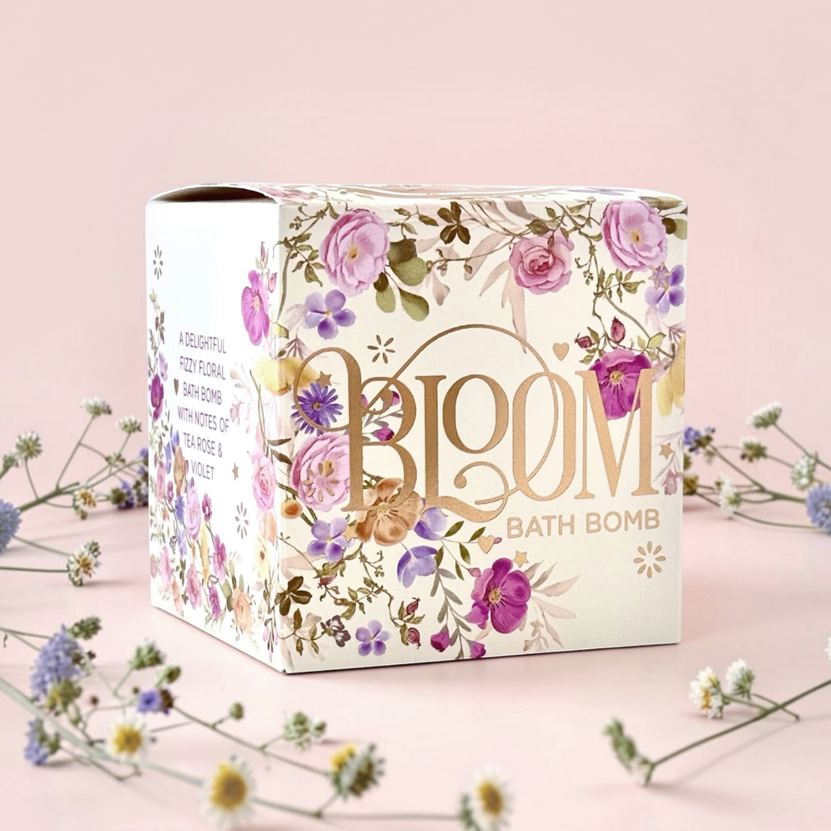 Bloom bath bomb with floral design on a pink background