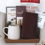 Coffee and Treats comes with a Wildflower Pop Beehive Stoneware Mug, Tan faux leather travelers notebook, Everton Toffee Pretzels, Backporch Coffee Roasters Pour Over Pack, Moonstruck Dark chocolate Espresso, pen, Sweets Chocolate Salt Water Taffy