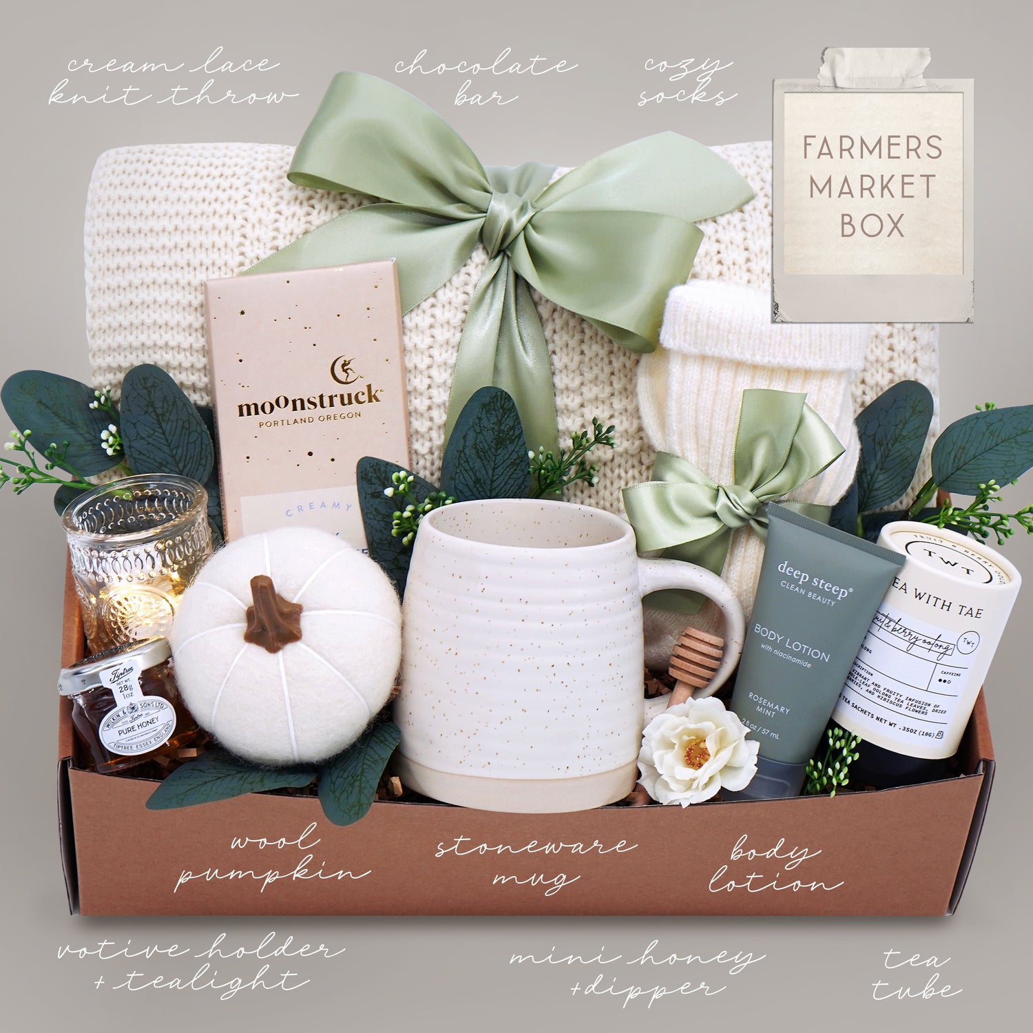 Gift box with various items including a mug, pumpkin, and candles on a neutral background.