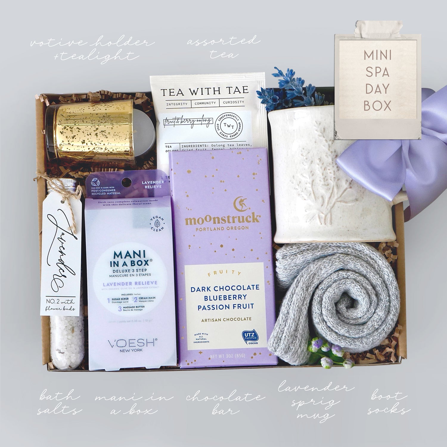 Lavender Gift box with various spa items including a candle, tea, and chocolate on a light gray background