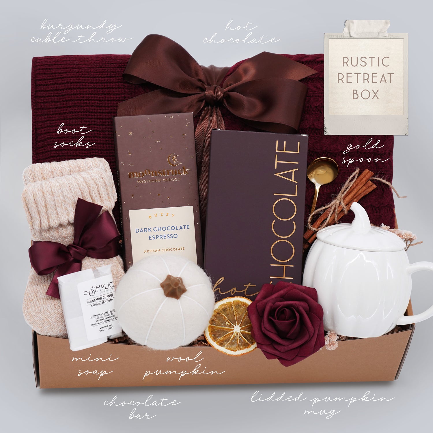 Gourmet gift box with hot chocolate, tea set, and other items on a light gray background