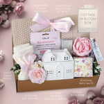 Cottage-themed gift box with various items on a pink background