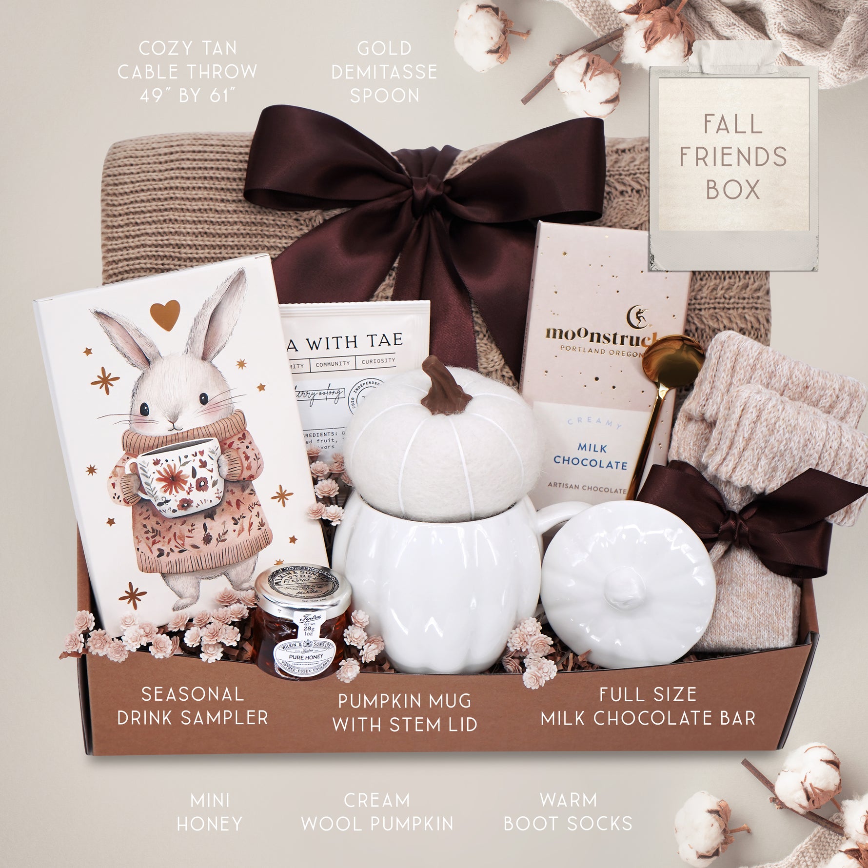 Gift basket with a blanket, drink sampler, and decorative items on a light gray background