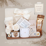 Wildflower Pop Sending a Hug Blanket gift box, with cream lace knit blanket, tea sampler, cream knit socks, hug in a jar soy wax candle, Wildflower Pop Heart ceramic mug, Moonstruck Milk Chocolate bar, and muscle soak