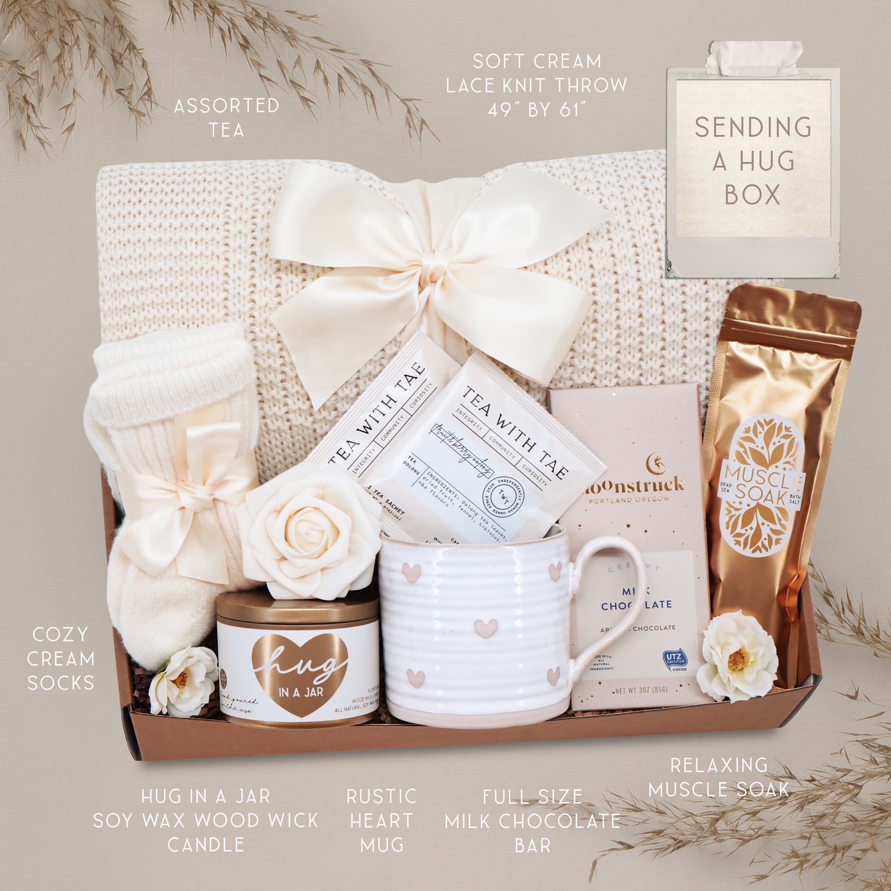 Wildflower Pop Sending a Hug Blanket gift box, with cream lace knit blanket, tea sampler, cream knit socks, hug in a jar soy wax candle, Wildflower Pop Heart ceramic mug, Moonstruck Milk Chocolate bar, and muscle soak