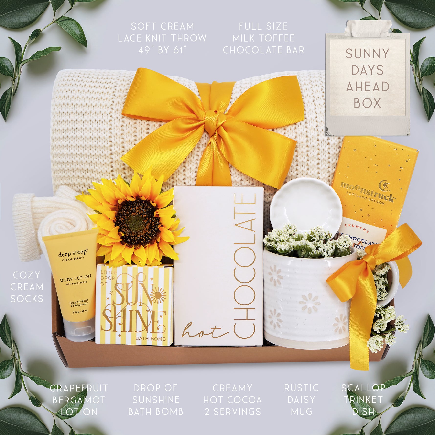 Wildflower Pop Sunny Days Ahead blanket gift box with a cream lace knit blanket, Wildflower Pop daisy ceramic mug, scallop trinket dish, moonstruck milk chocolate and toffee bar, little drop of sunshine bath bomb, faux sunflower, deep steep lotion, and cream knit socks