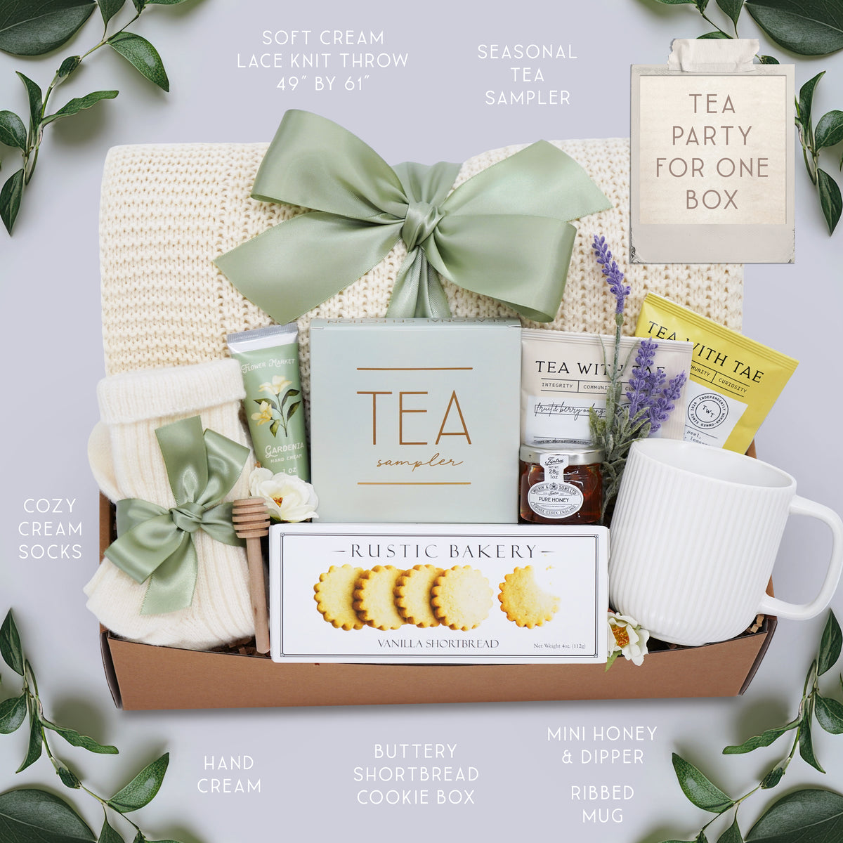 Wildflower Pop Tea Party for One comes with a cream lace knit blanket, cream knit socks, Flower Market Gardenia hand cream, Tea Sampler, Rustic Bakery shortbread cookies, ribbed white ceramic mug, mini honey and dipper