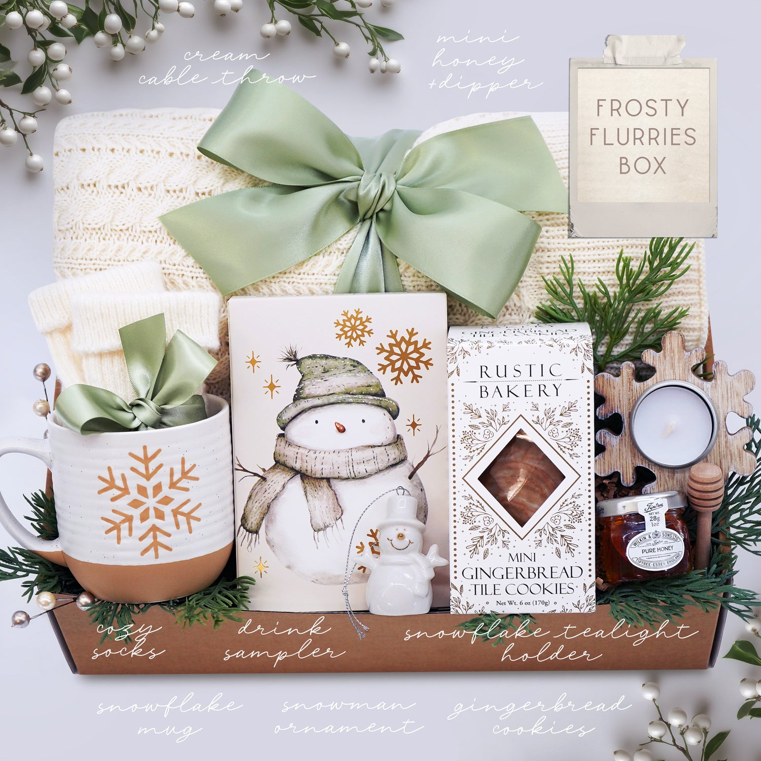 Wildflower Pop Frosty's Flurries Blanket Box with blanket, socks, Mini Gingerbread Cookies, drink sampler, ceramic snowman ornament, wooden snowflake votive and tea light, mini honey and dipper. 