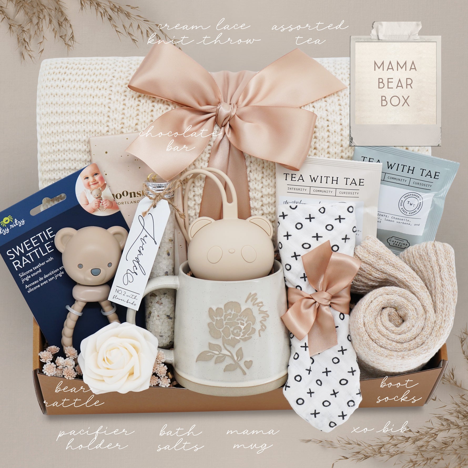 Baby gift box with various items including a mug, rattle, and tea set, branded 'Mama Bear Box'.