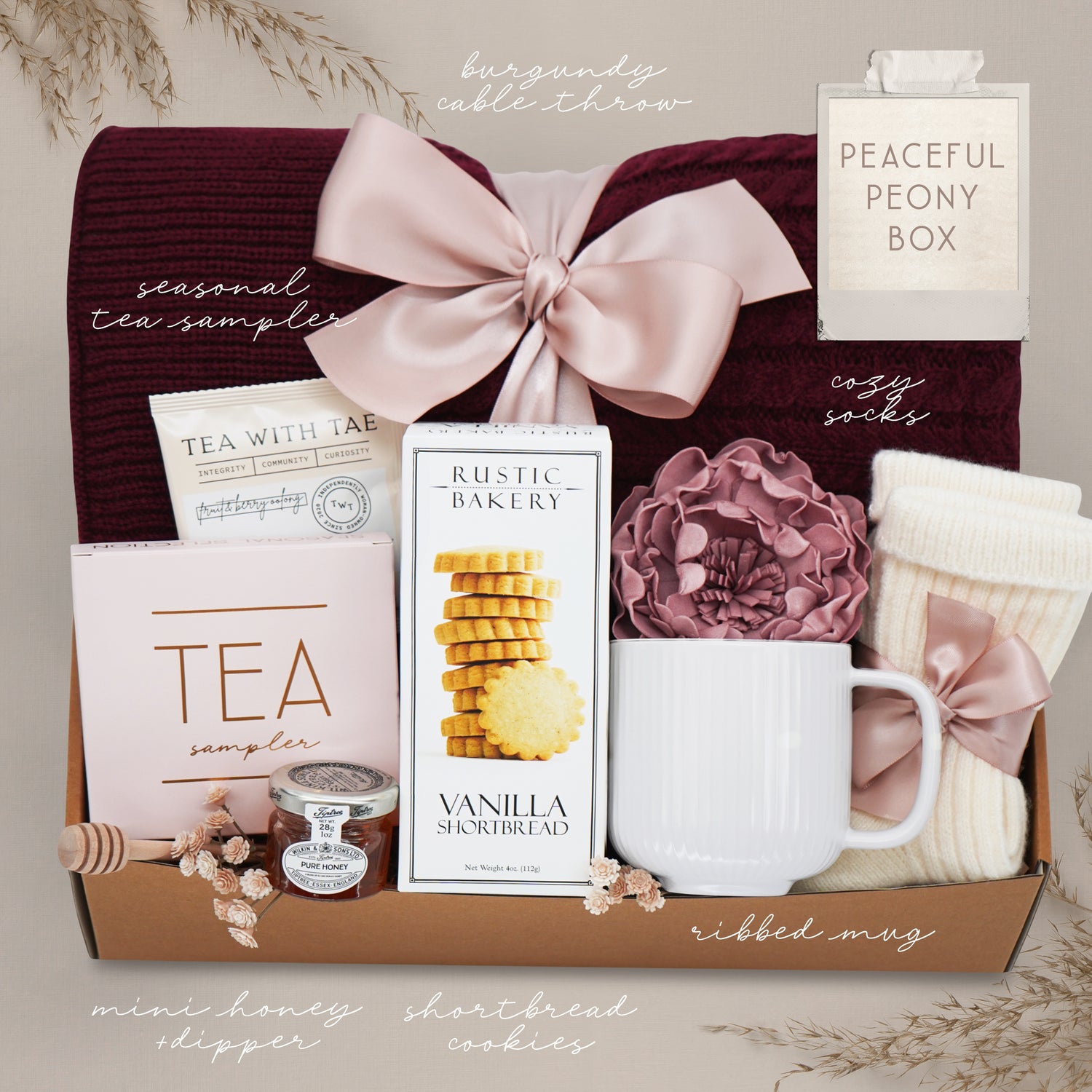 Gift box with tea, cookies, mug, and other items on a neutral background